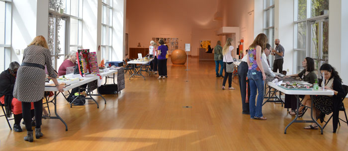 Artists sitting behind tables at the Harn Museum of Art show their touchable artwork to visually impaired visitors. 