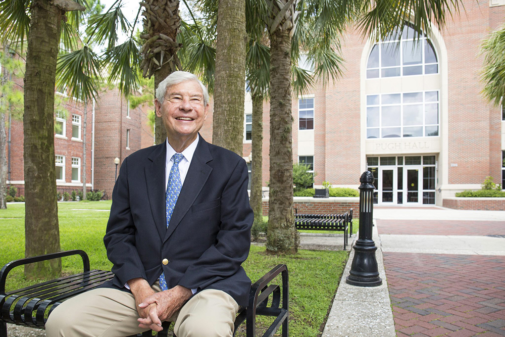 Former Sen. Bob Graham sits on a bench before Pugh Hall at the University of Florida.