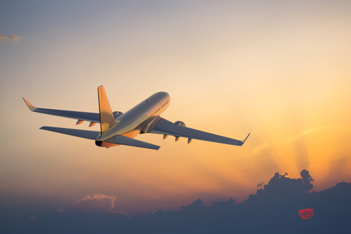 A passenger jet takes off into a sunset or maybe a sunrise. 