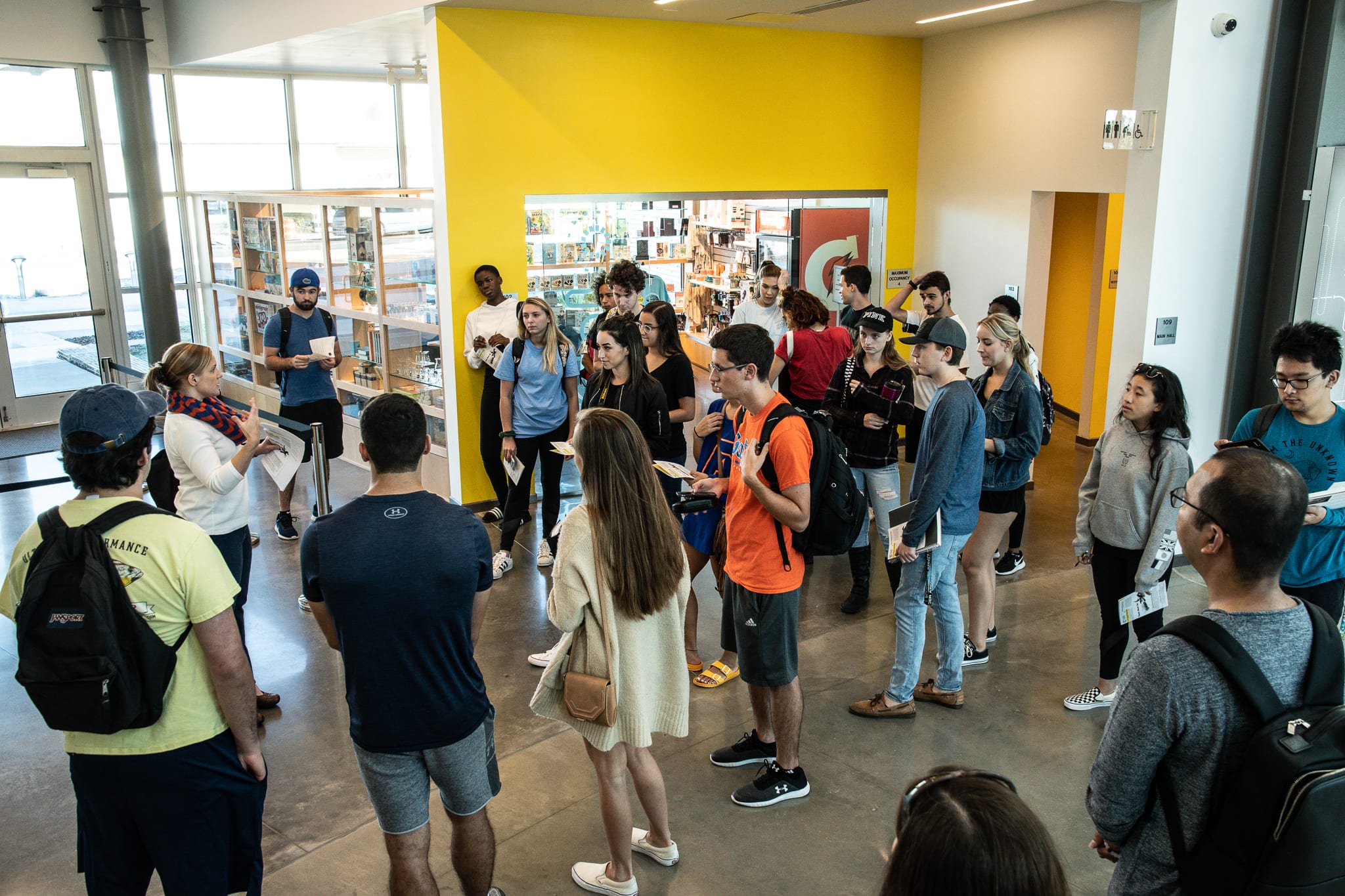 Students gather around a person speaking. 