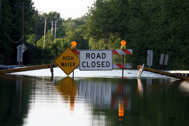 a closure sign in a flooded road on a sunny day