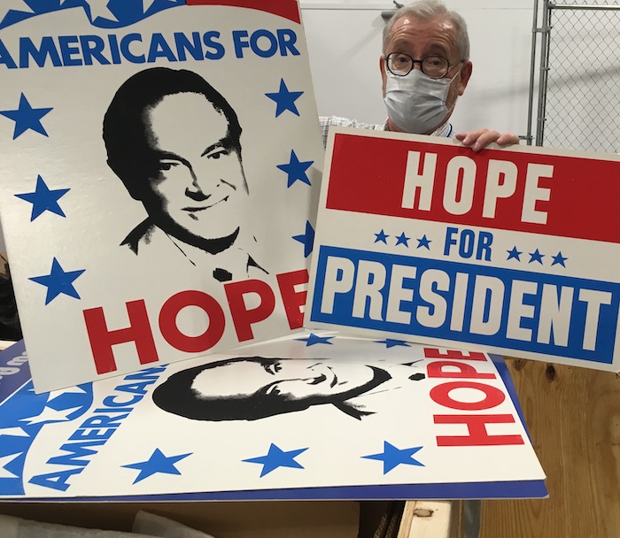 Jim Liversidge holds up prop campaign signs reading 