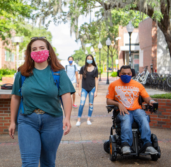 Students wearing asks cross through Turlington Plaza