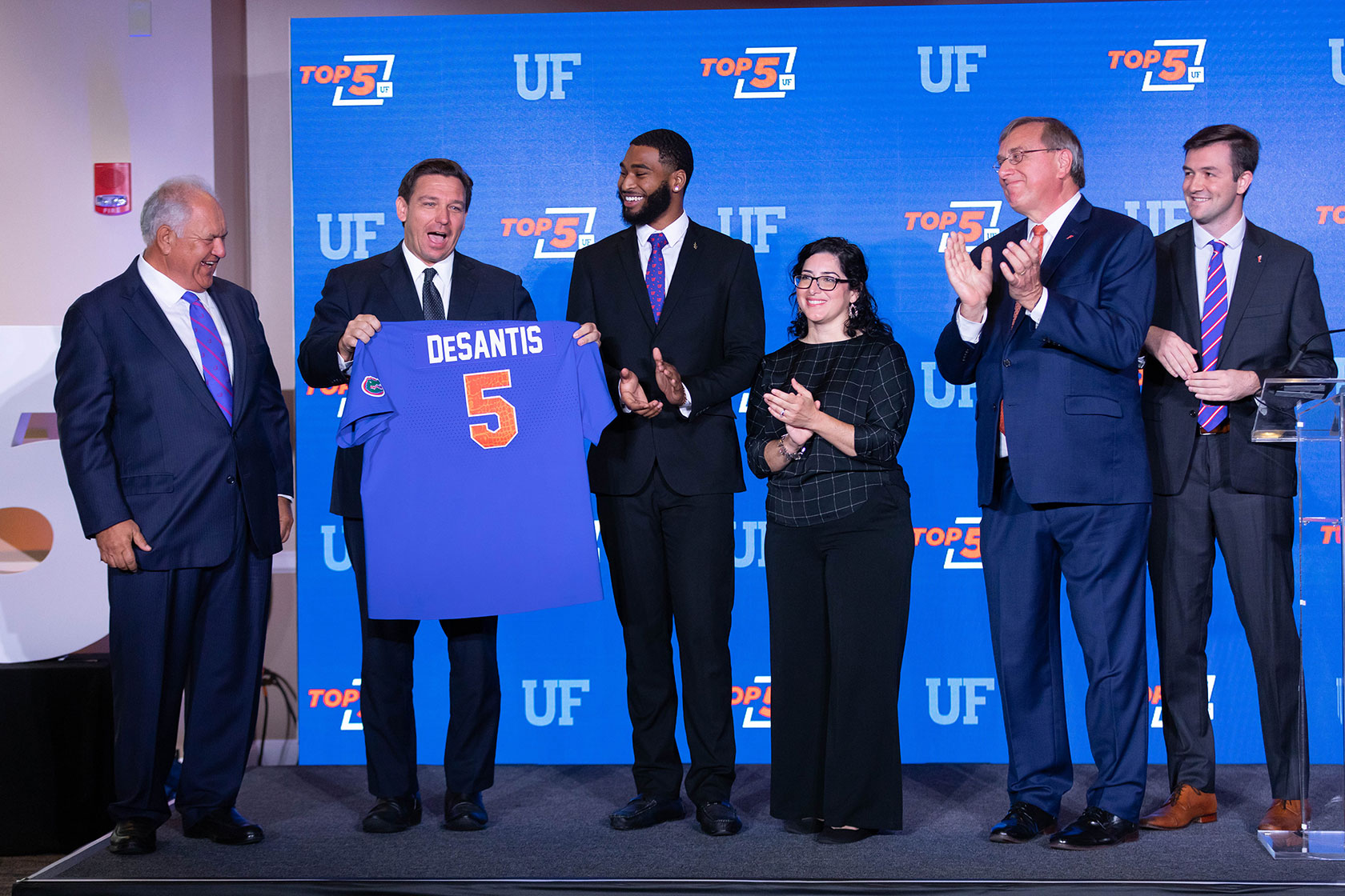 Florida Gov. Ron DeSantis is presented with a University of Florida jersey with the No. 5, representing the university's recent ranking as Top 5 among the country's public universities.