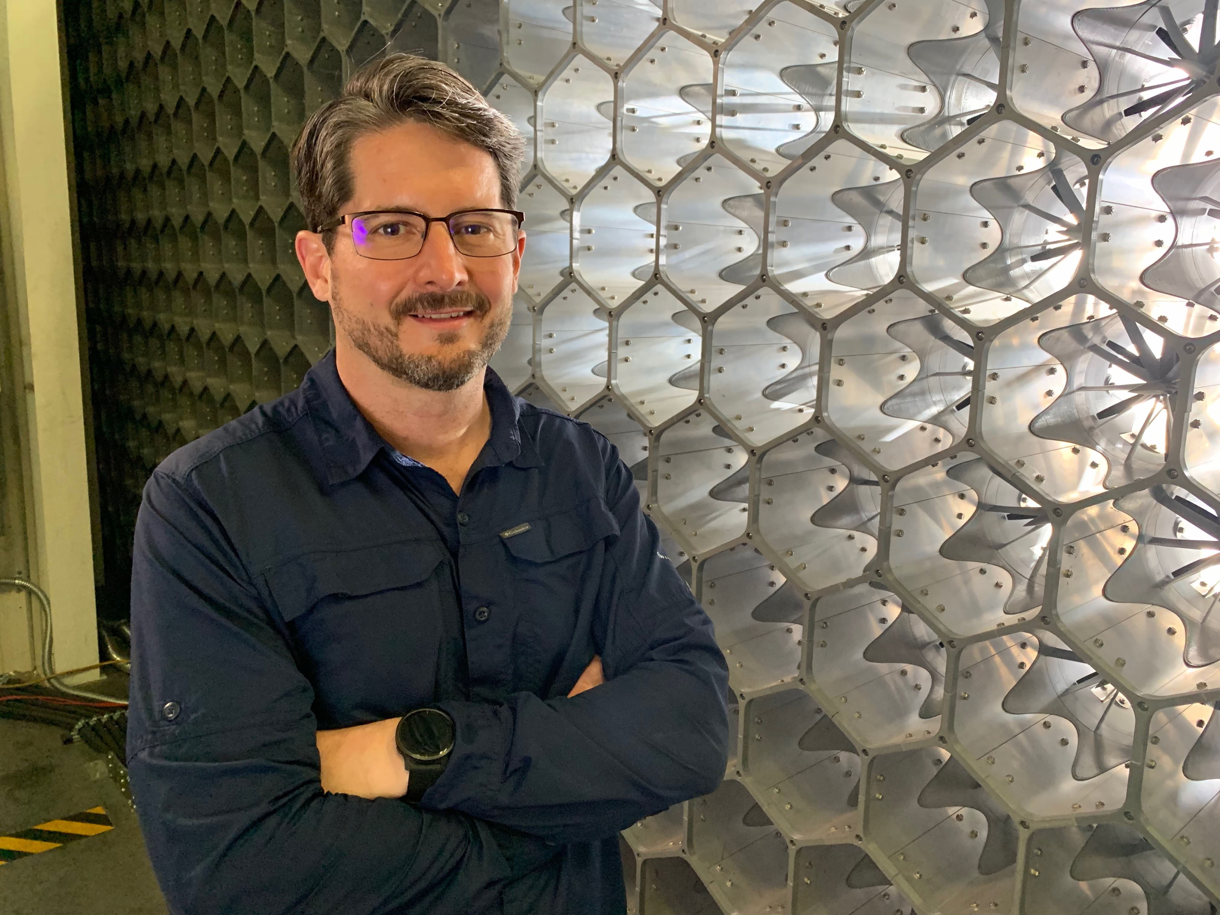 Forest Masters stands in front of honeycomb structured cells designed to capture wind speed