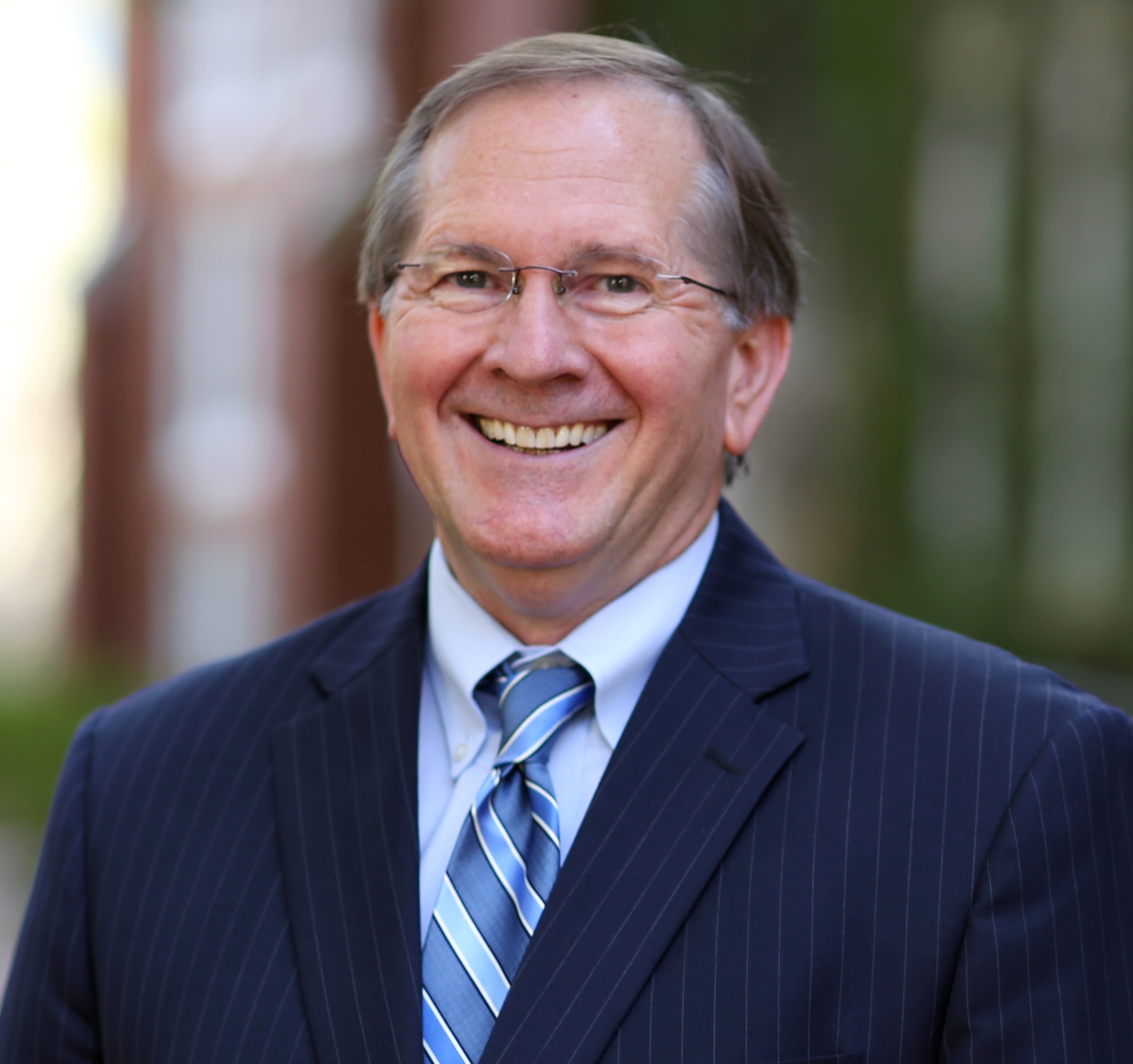 Mark Jamison smiles for a professional headshot. He is wearing a suit and tie.