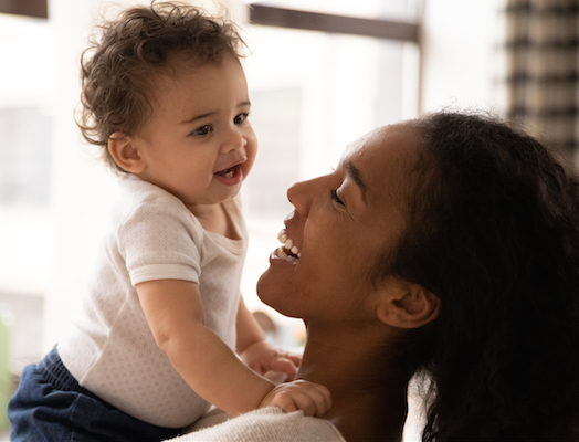 A cute baby babbles to mother while being held 