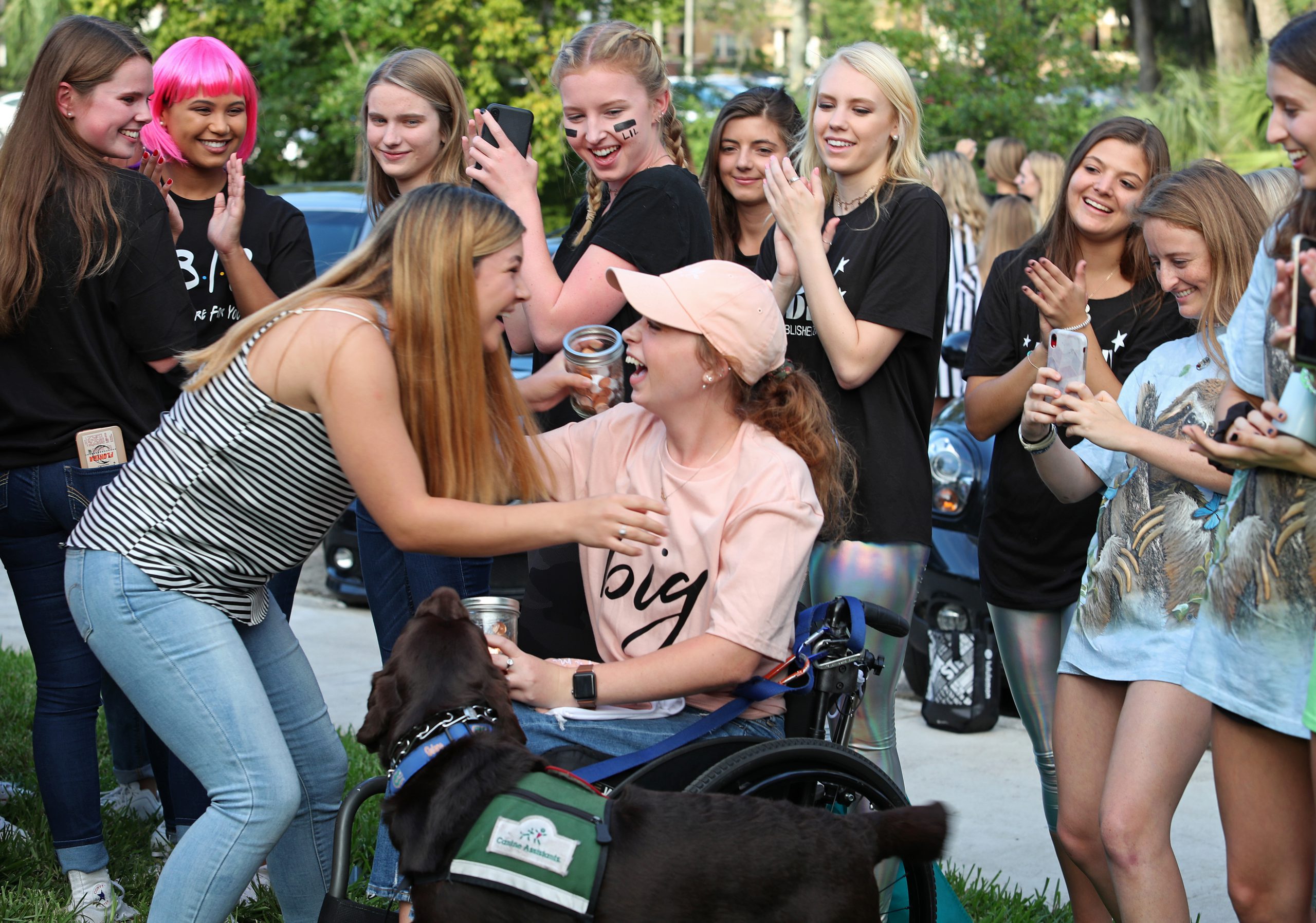 Two women surrounded by a group of their sorority sisters hug