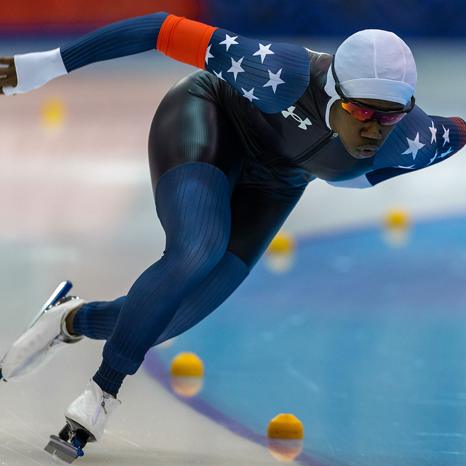 A female long track speed skater races on the ice.