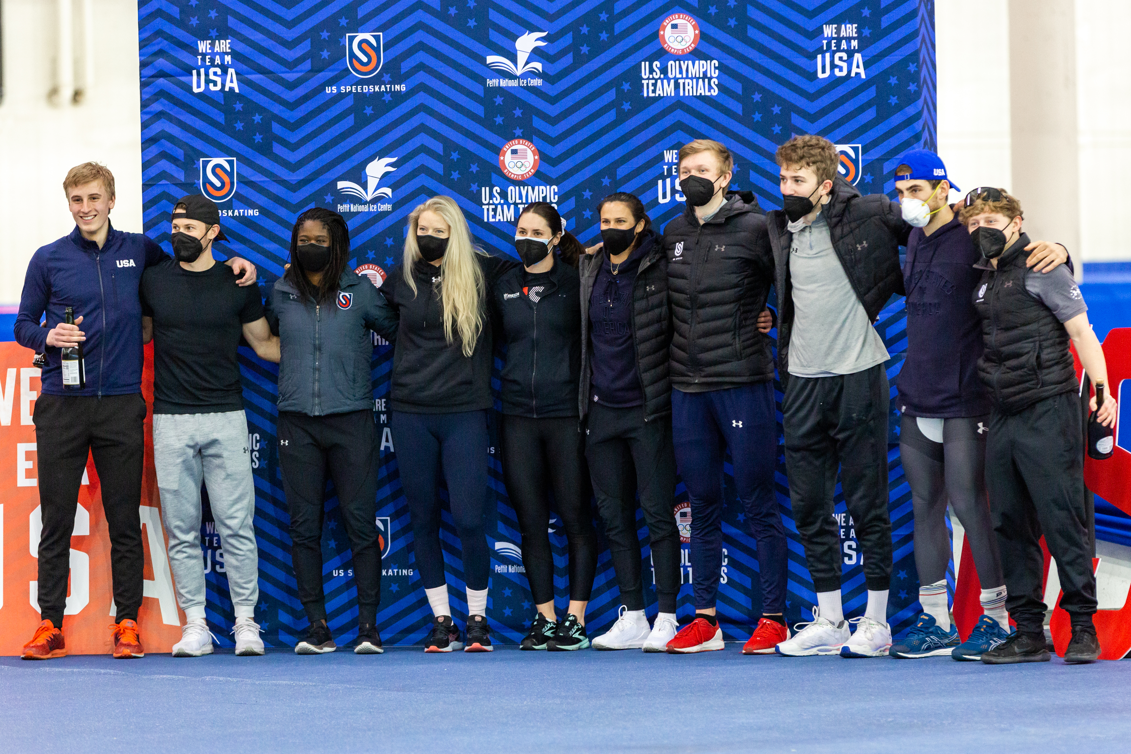 A group shot of several Olympic athletes standing next to each other posing for a picture.
