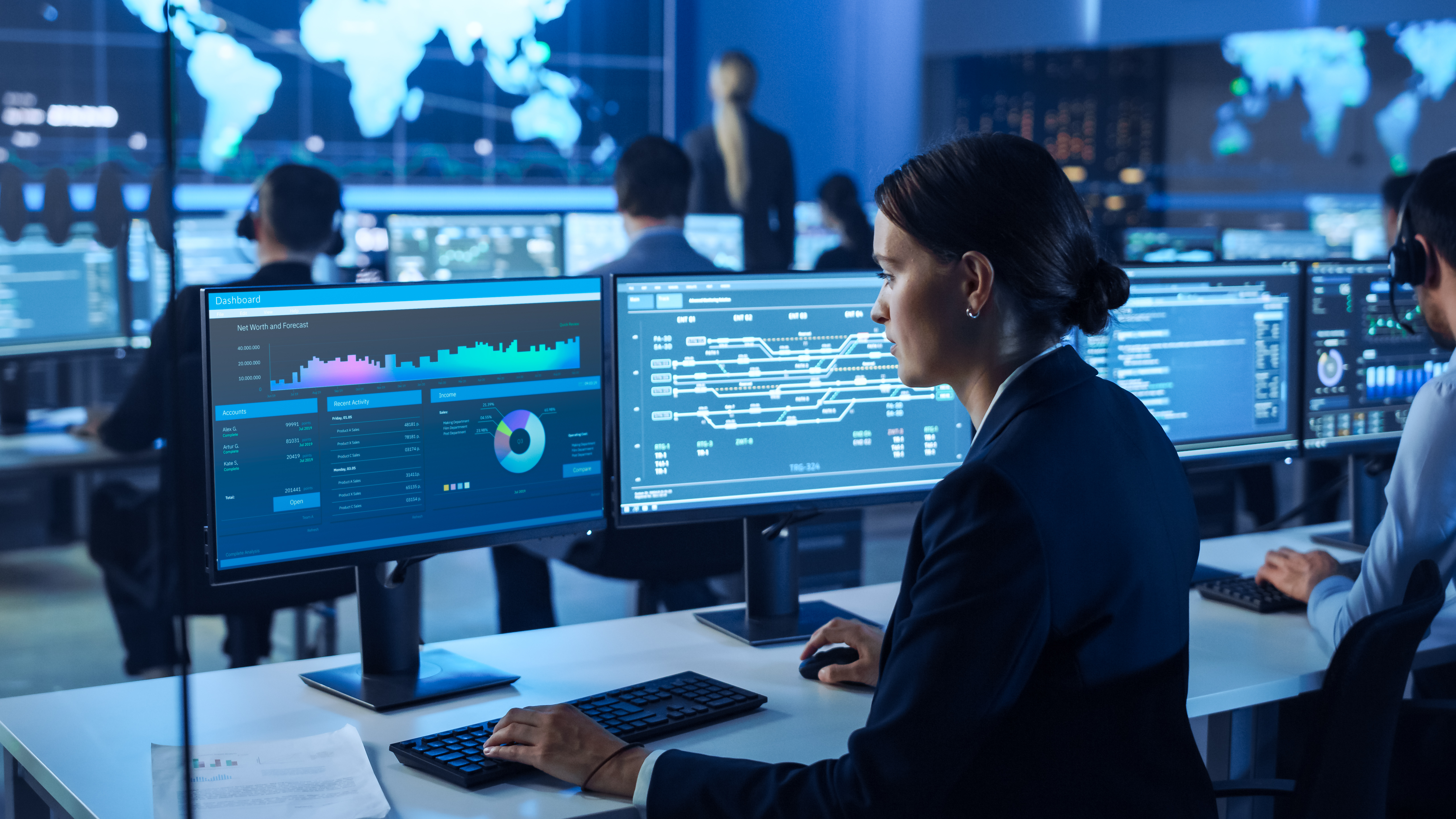 Employees sitting at computers monitoring screens in a control room.