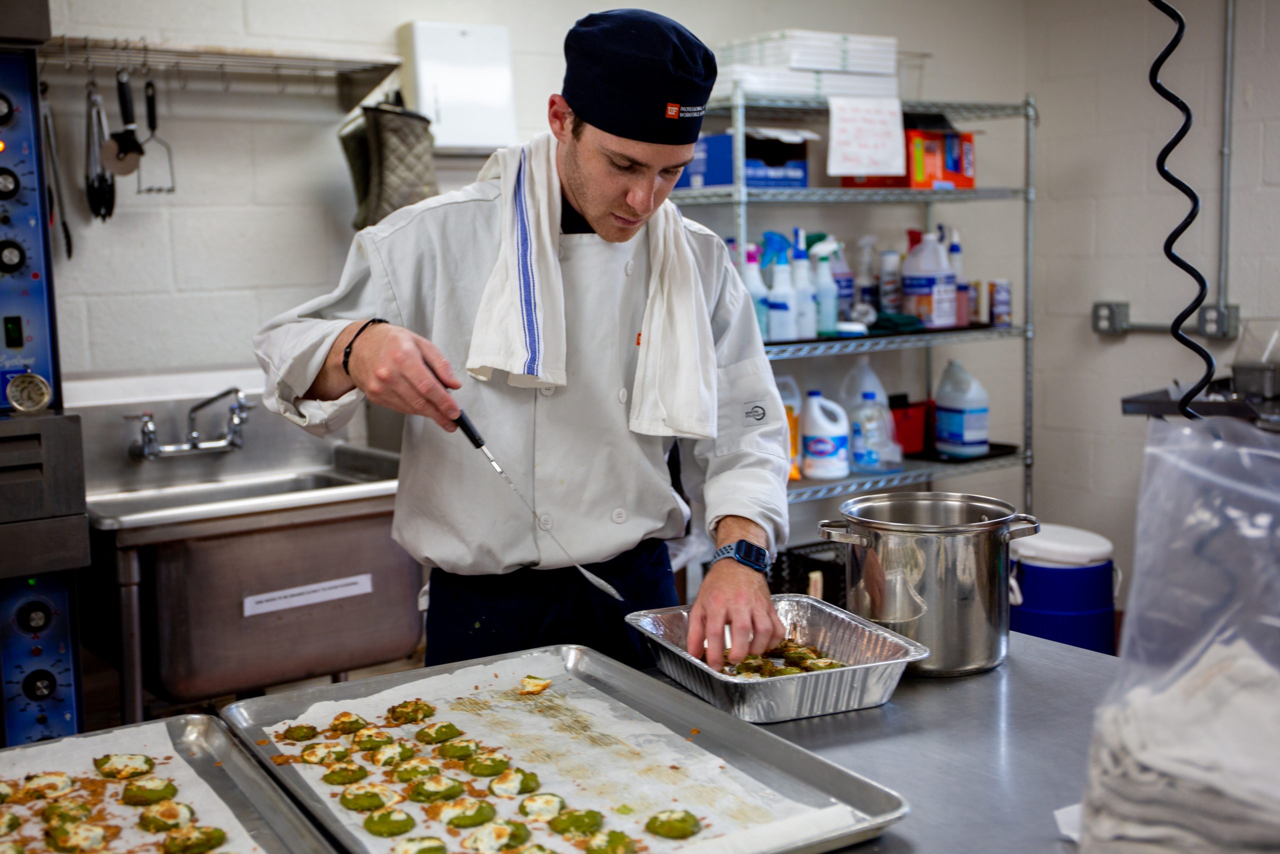 A man transfers food from one tray to another with a spatula 