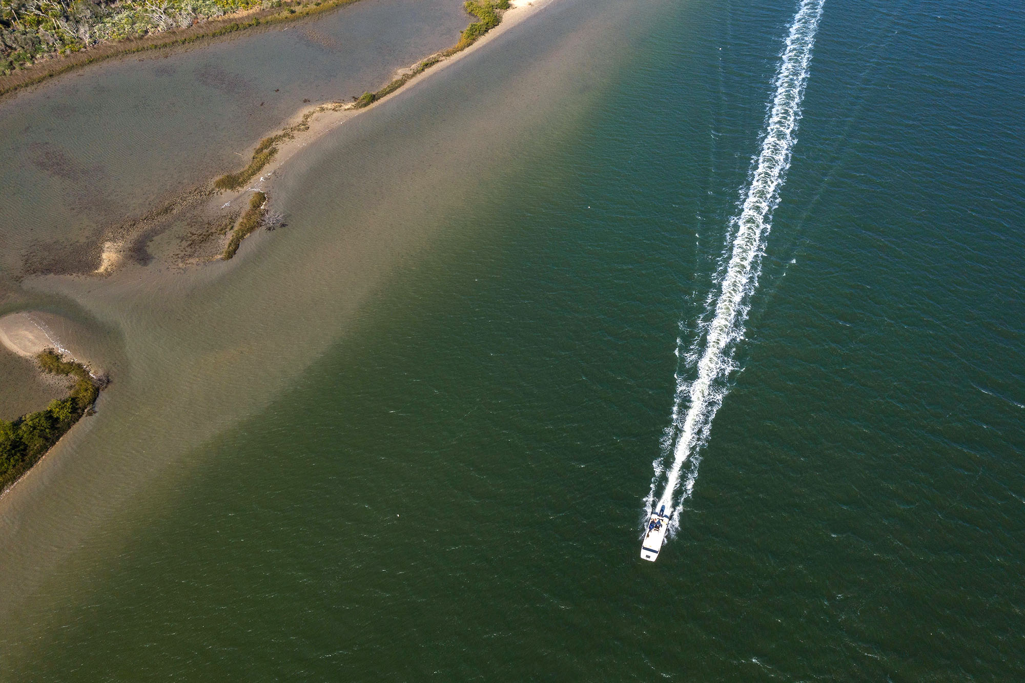 An aerial photo of a boat driving along the coast. 