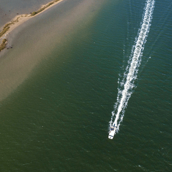 An aerial photo of a boat driving along the coast. 