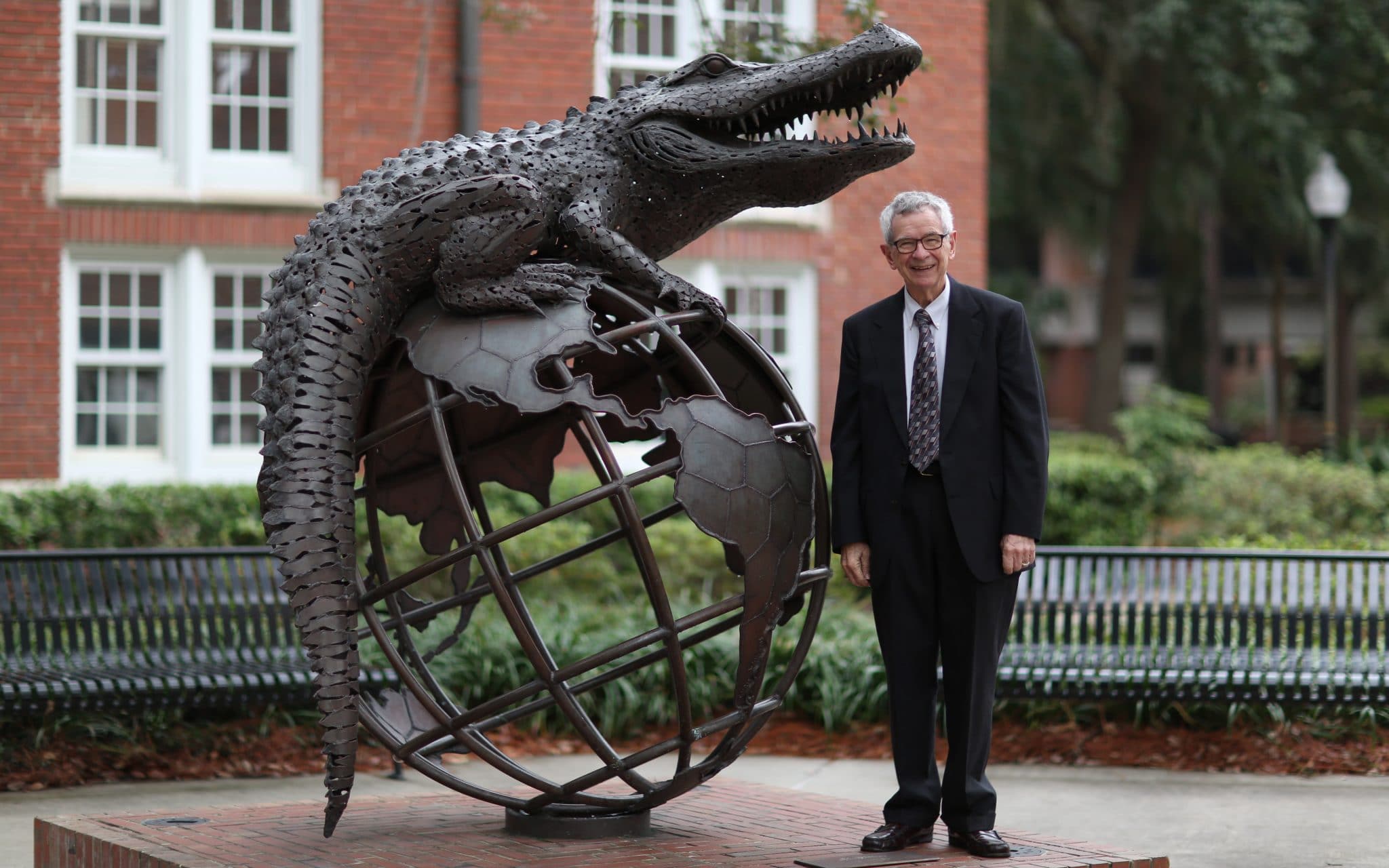 A man stands by a steel structure that features an alligator on top of the world. 