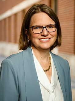 A headshot of a woman with a building in the background.