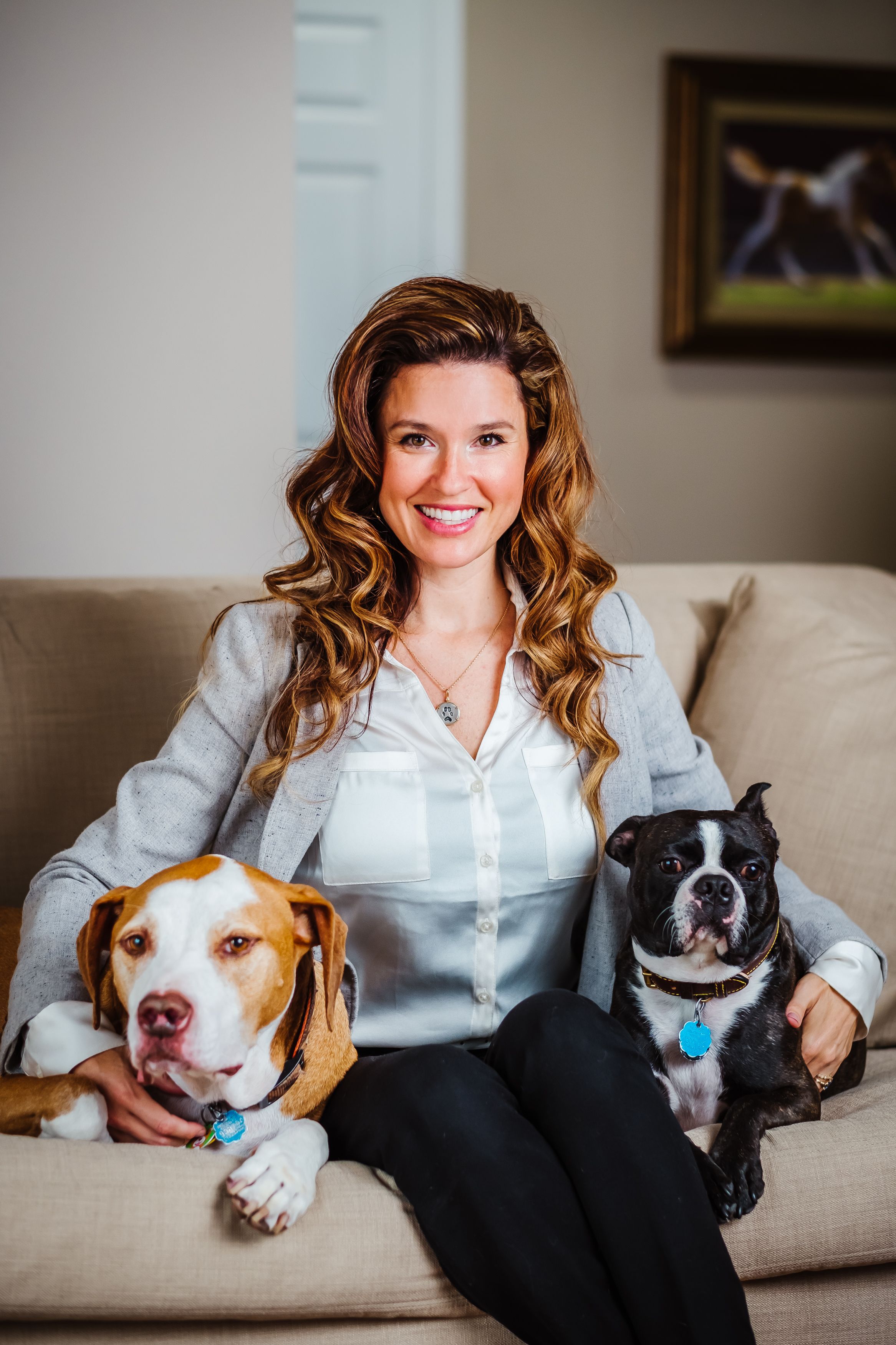 A woman sitting on a couch with two dogs sitting on either side of her.