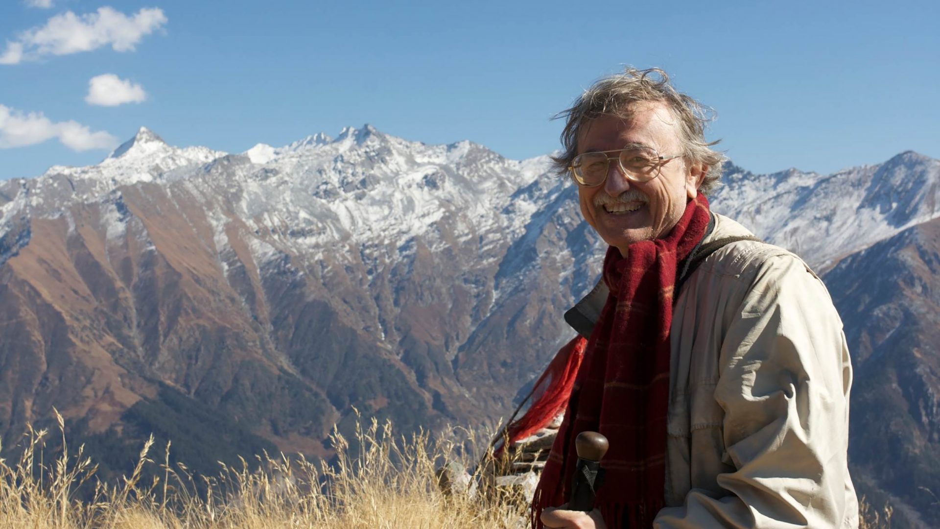 A man standing in a field with mountains in the background.