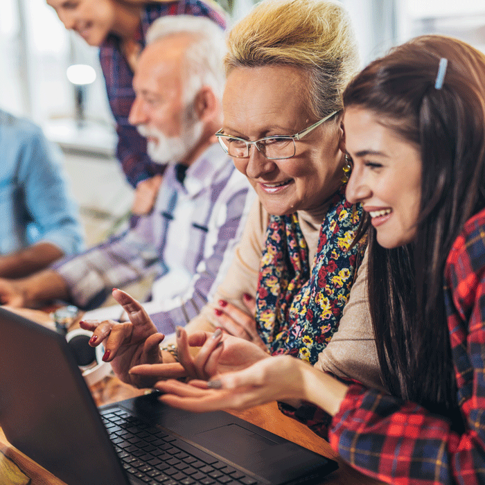 An older woman and a younger woman use a laptop together.