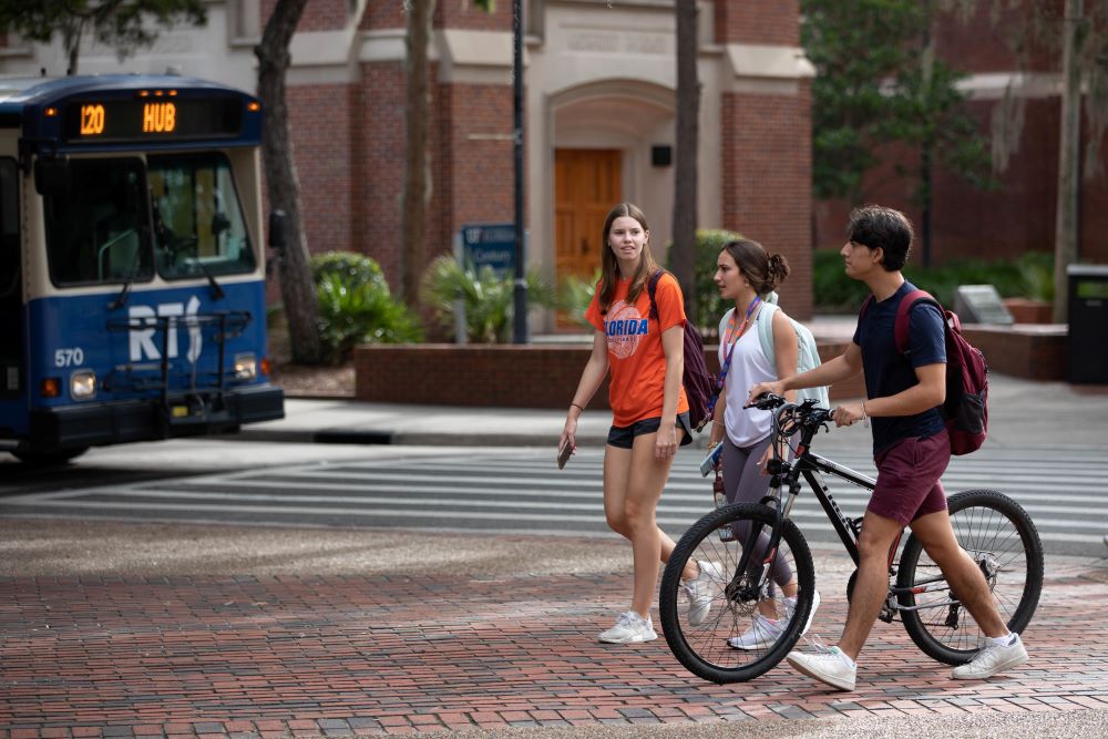Three students walking in the heart of UF campus