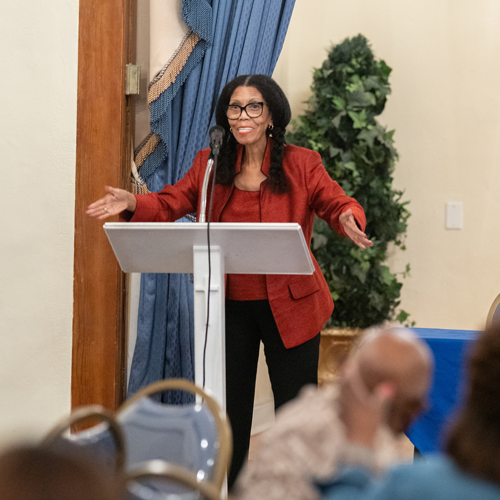 A woman gives a speech at a podium on stage.