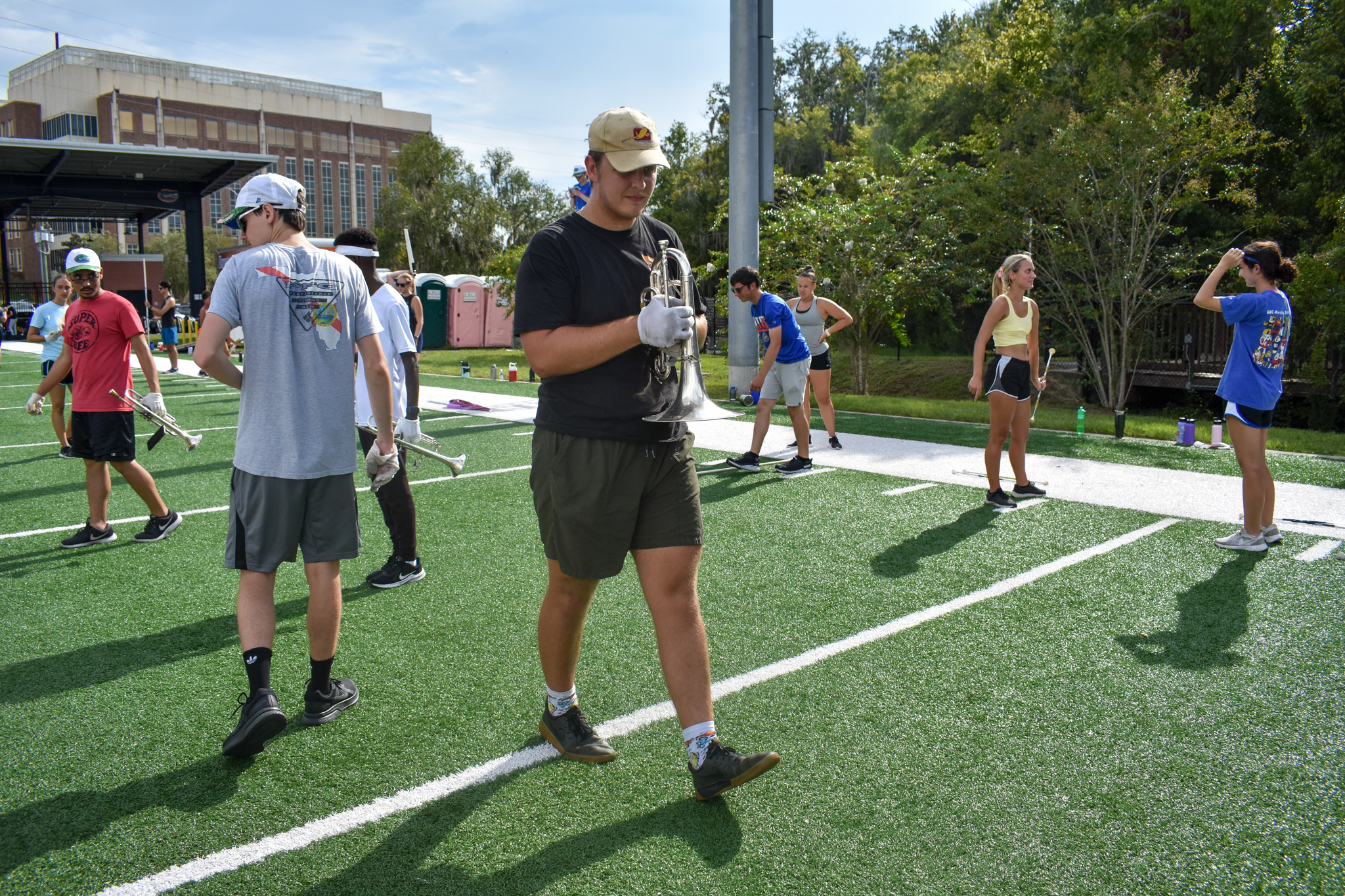 A student steps off a yard line on a football field while holding a mellophone.
