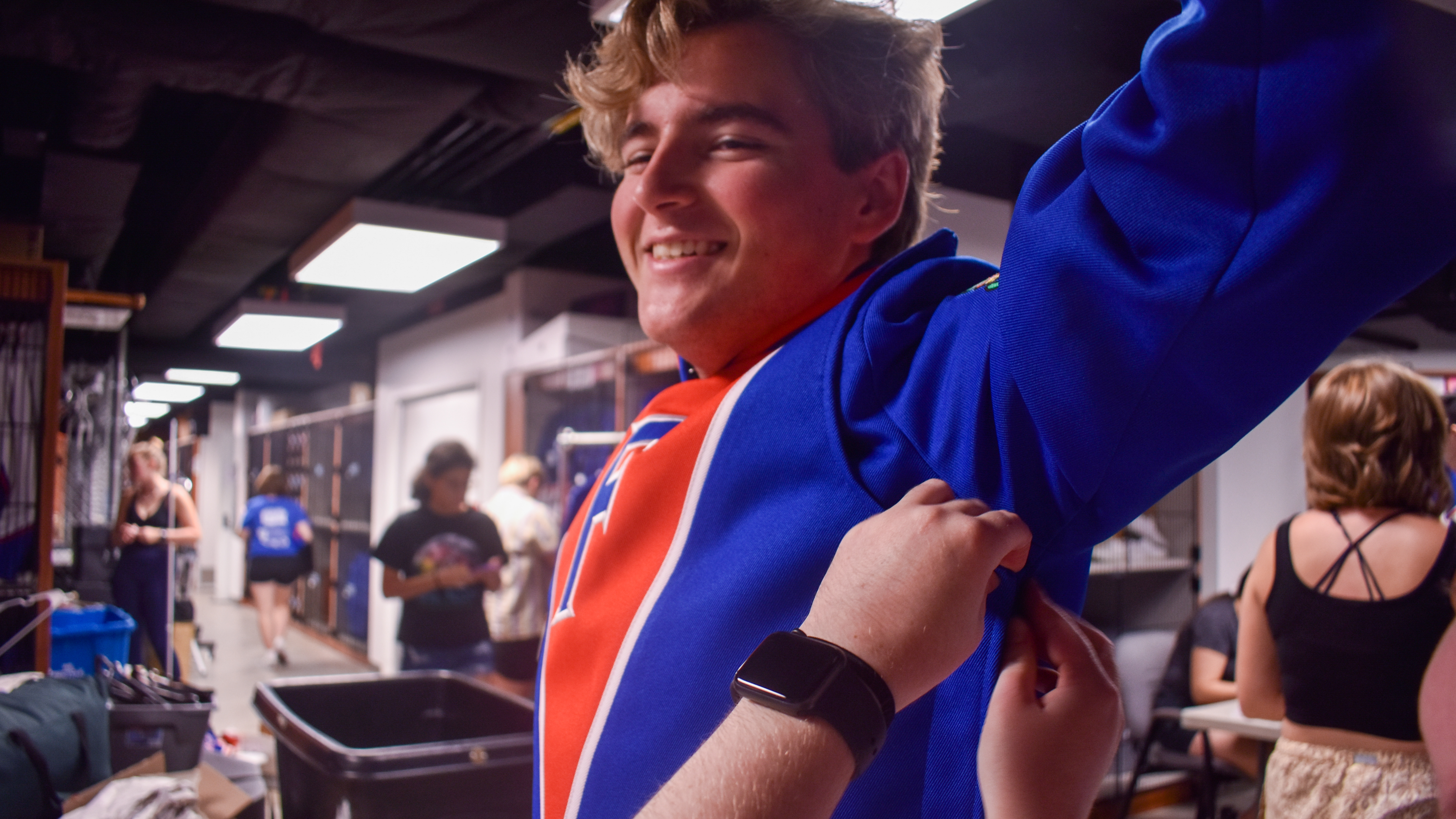 A student gets zipped into a marching band jacket.