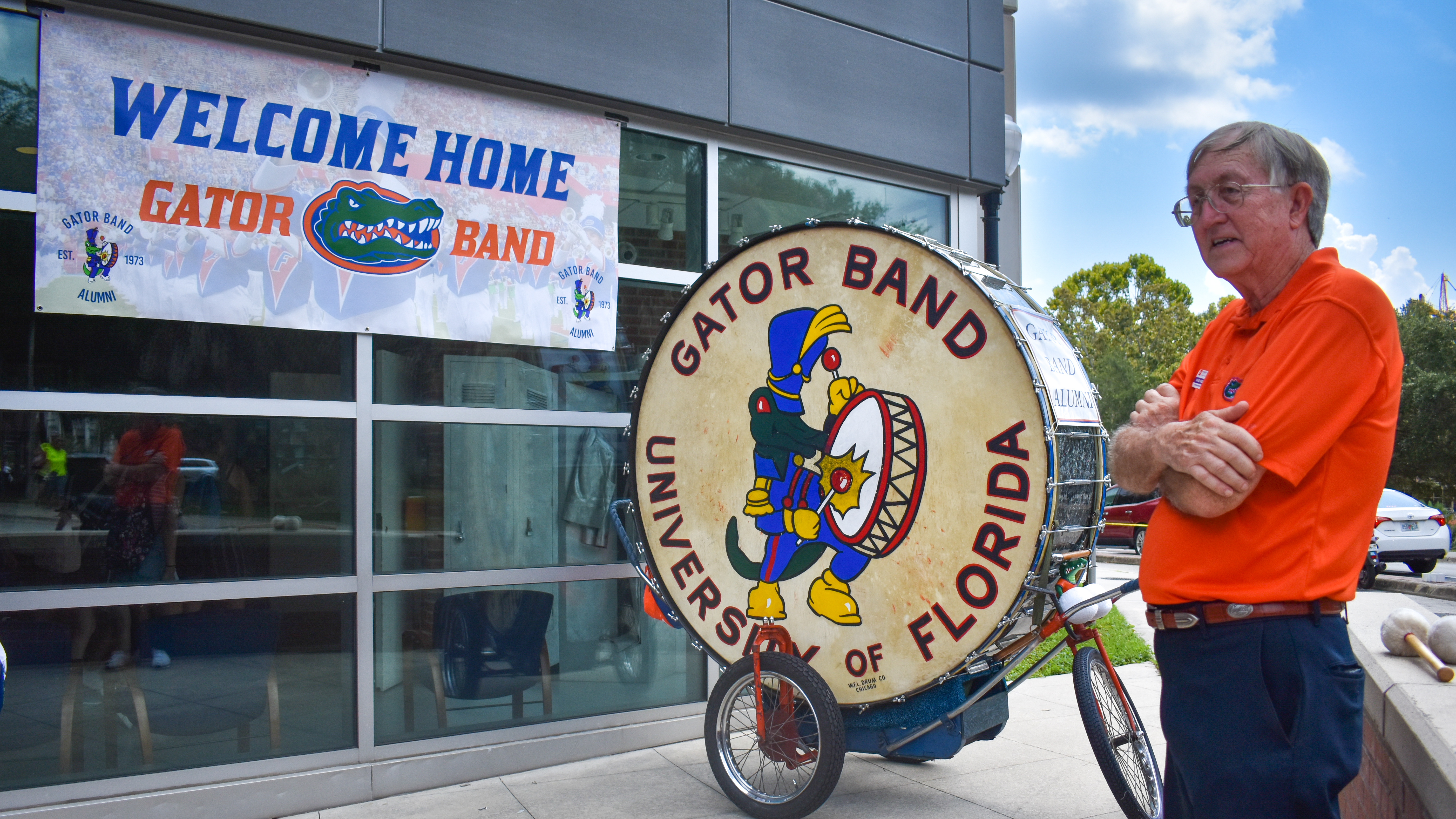 A man stands next to a giant drum outside a building.