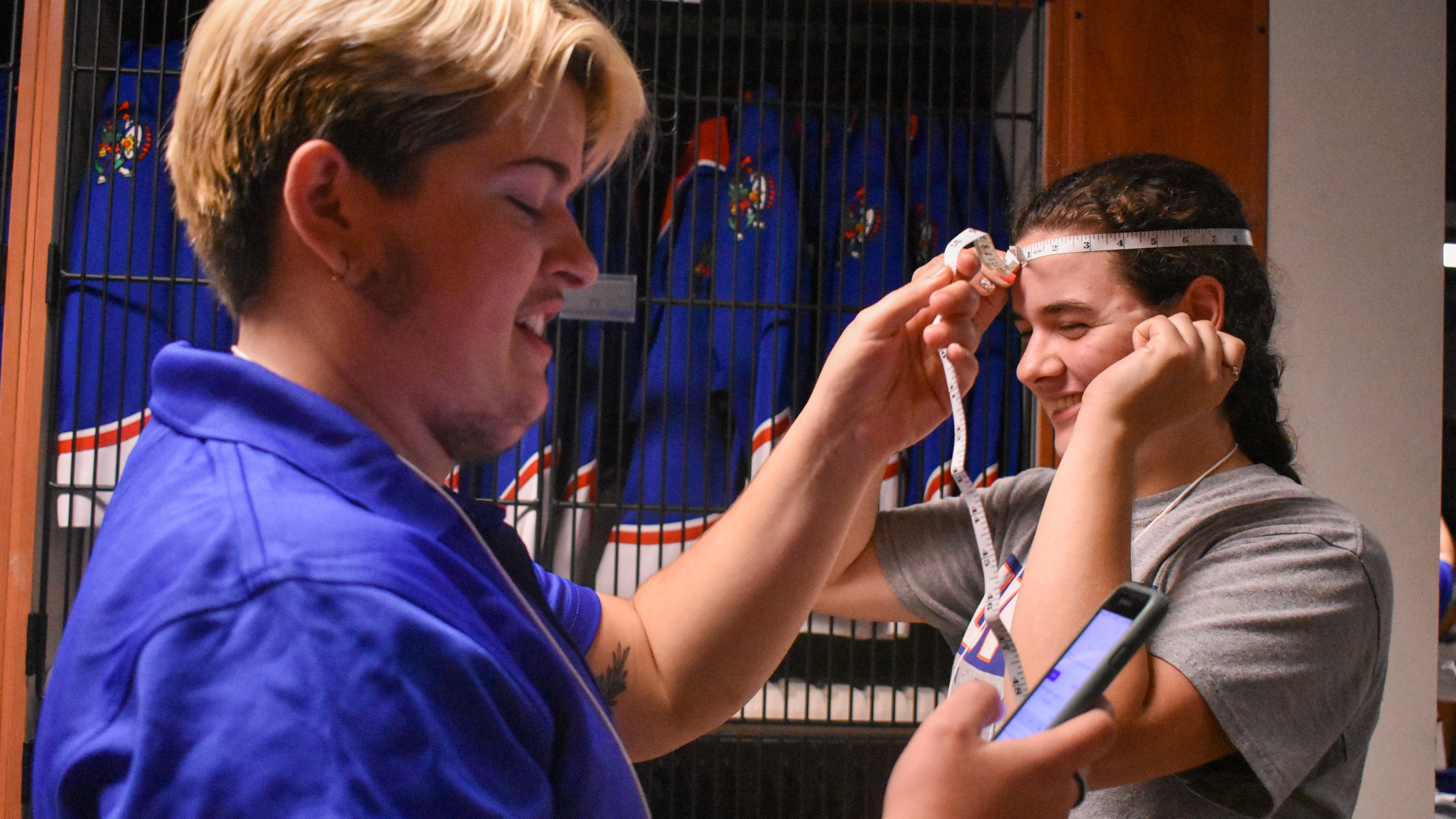 A student measures another student's head with a measuring tape.