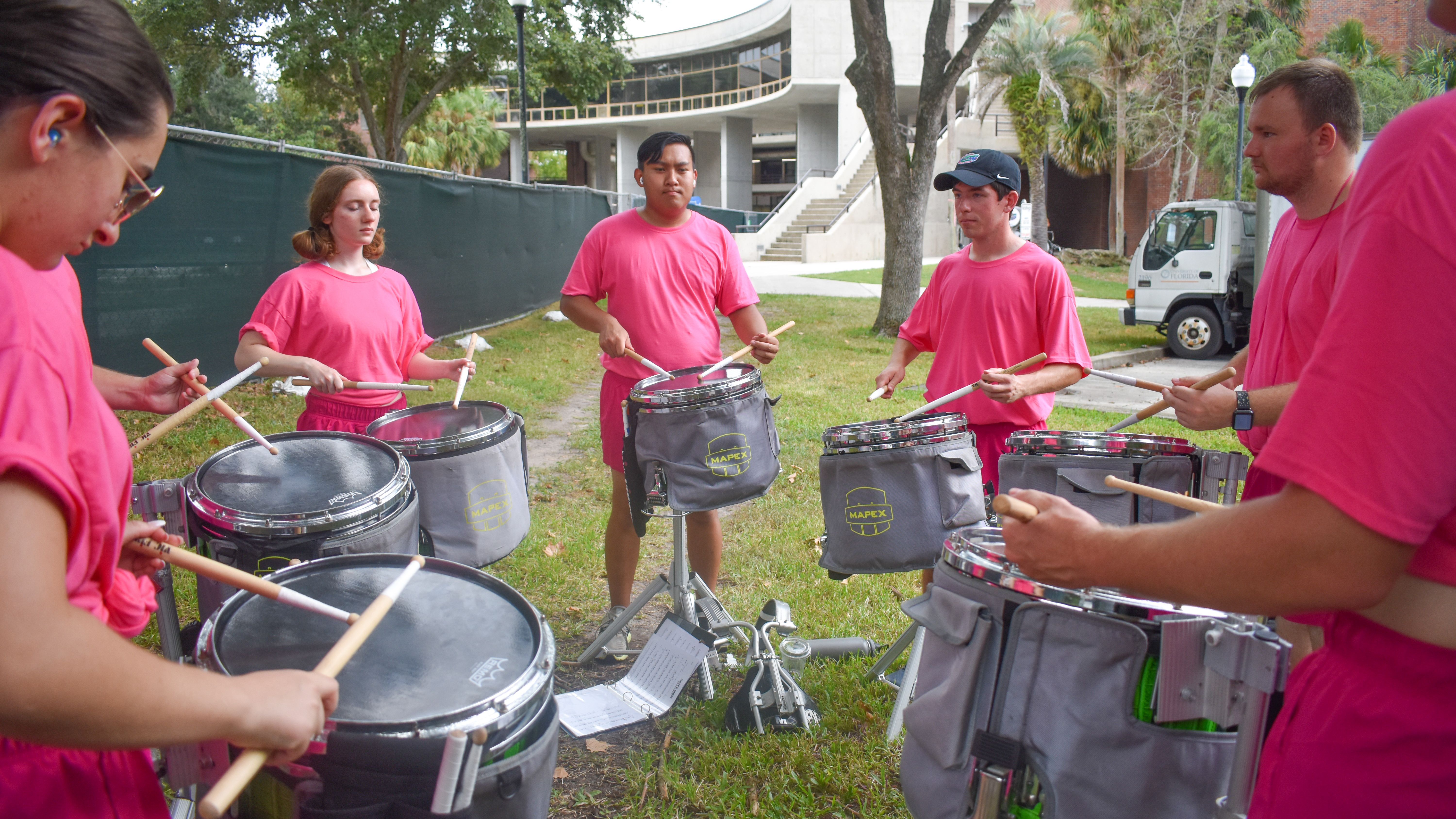 A group of snare drummers play in a circle.