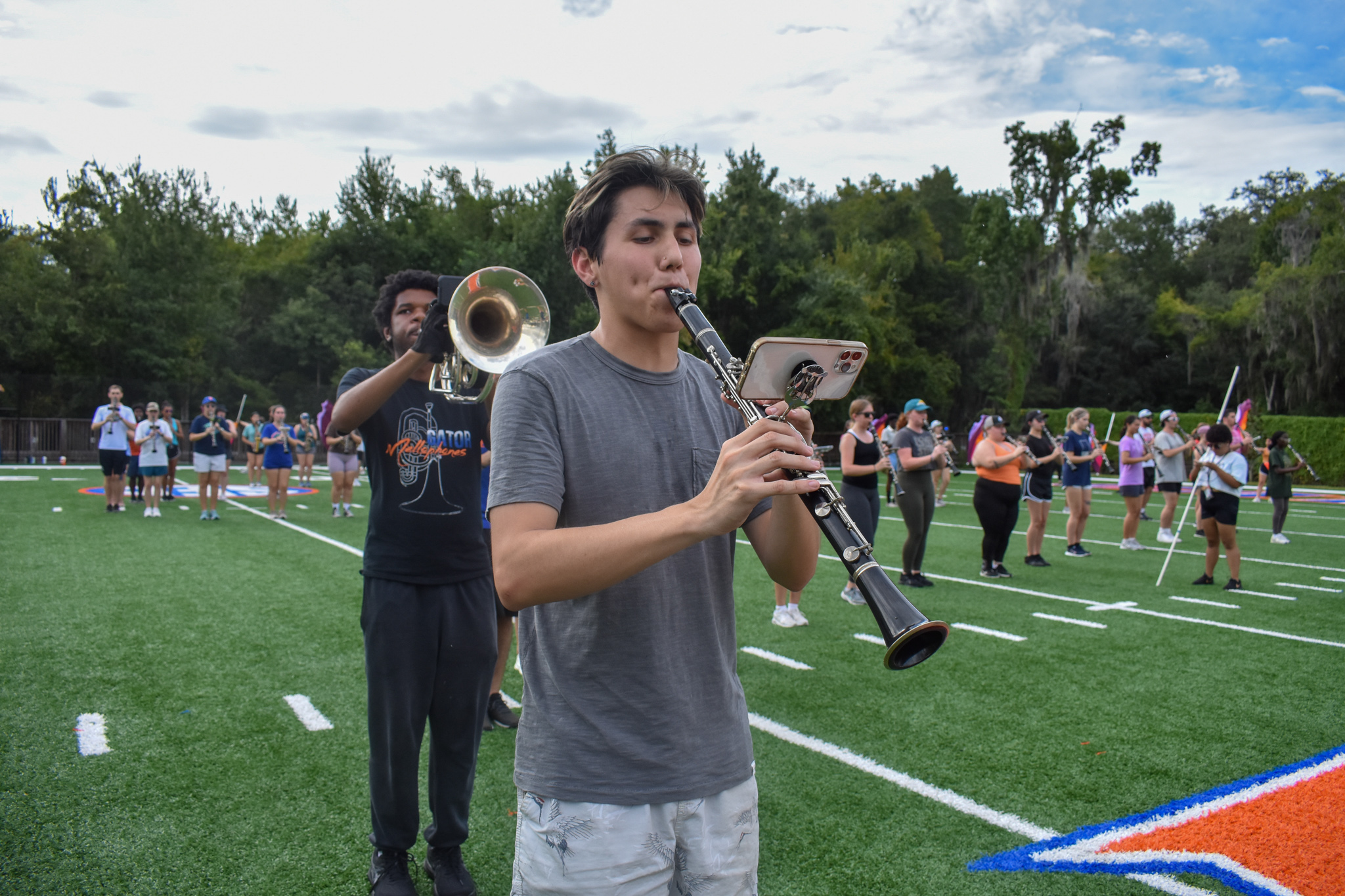 A student plays the clarinet with a phone attached to it that shows sheet music.