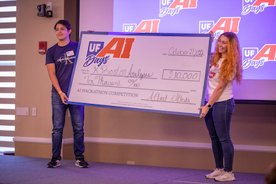 Two UF students holding oversized check for $10,000