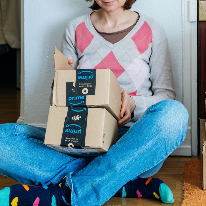 A woman sitting on the floor opening Amazon packages