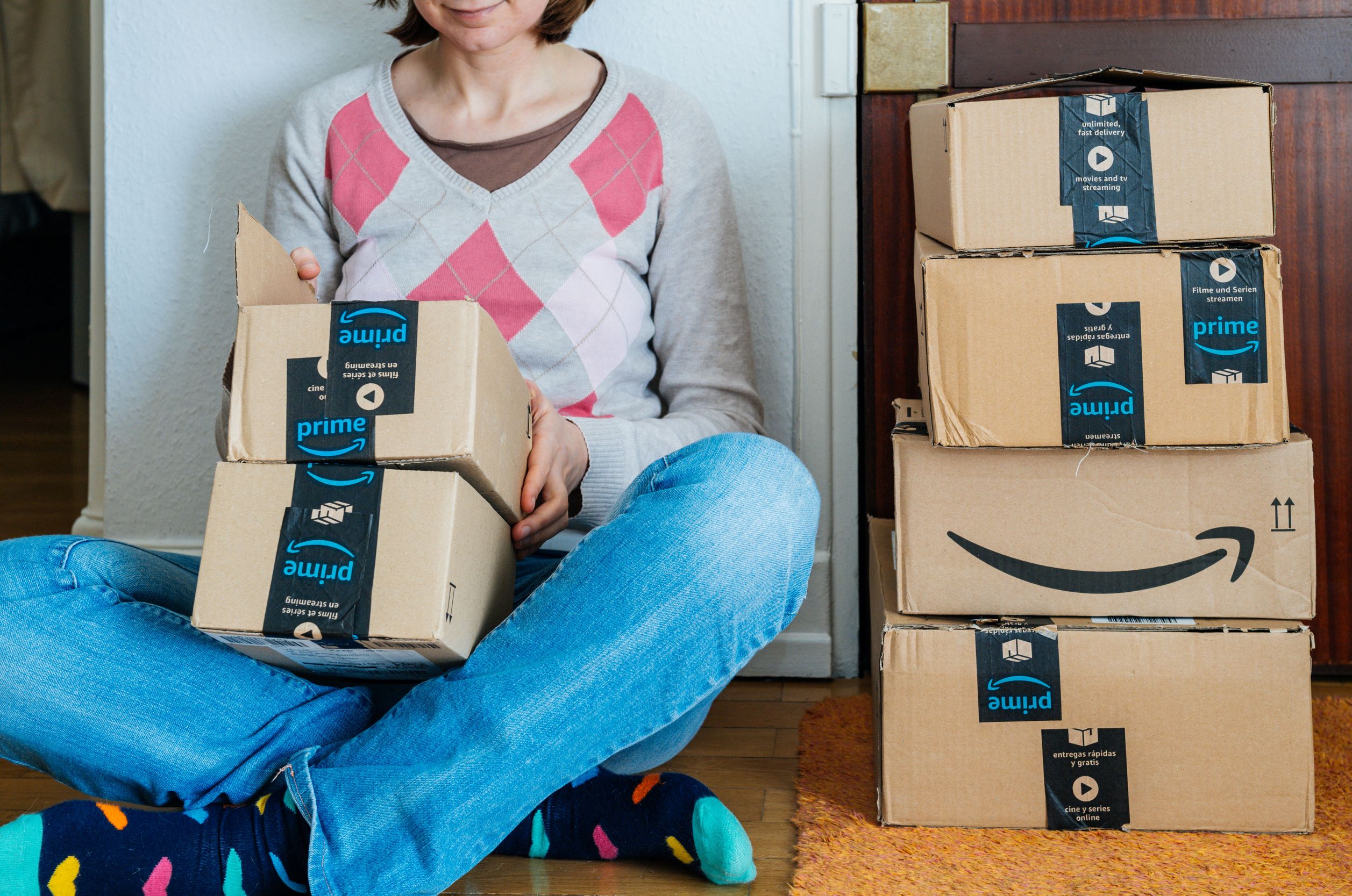 A woman sitting on the floor opening Amazon packages