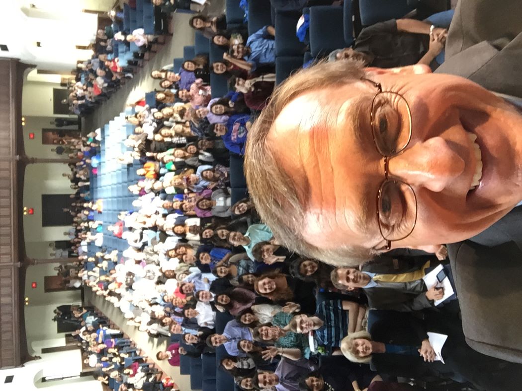 UF President Kent Fuchs takes a selfie from stage with large audience in background