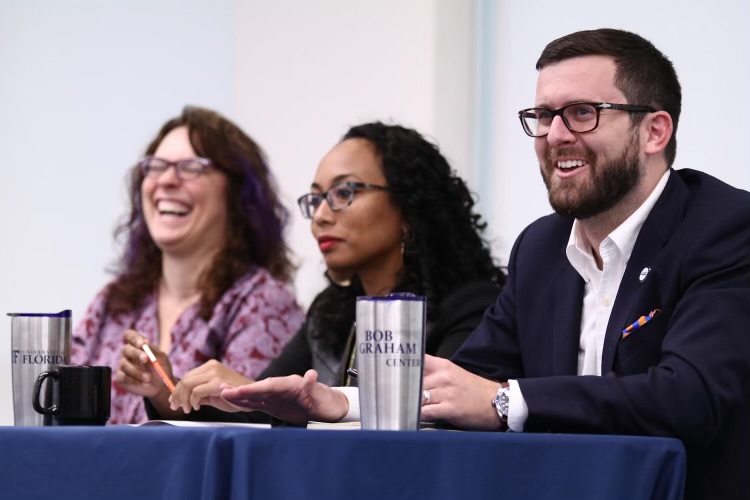 A photo of Chris Emmanuel with two other individuals sitting at a table at an event at the Bob Graham Center for Public Service.