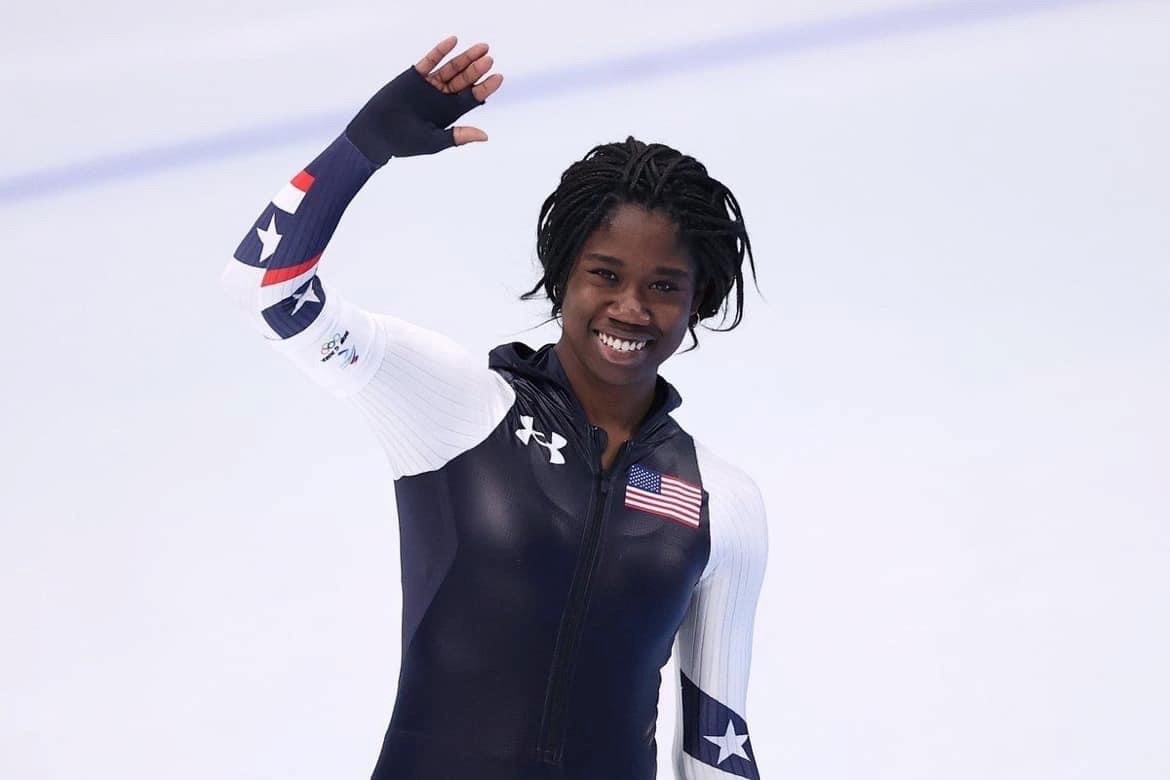 Olympic gold medalist Erin Jackson waving on an ice rink.