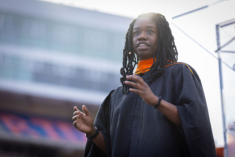 A woman speaks to a crowd of graduates and their family.