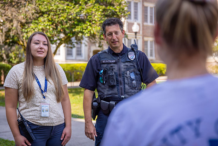 A civilian counselor and a uniformed police officer speak with a woman.