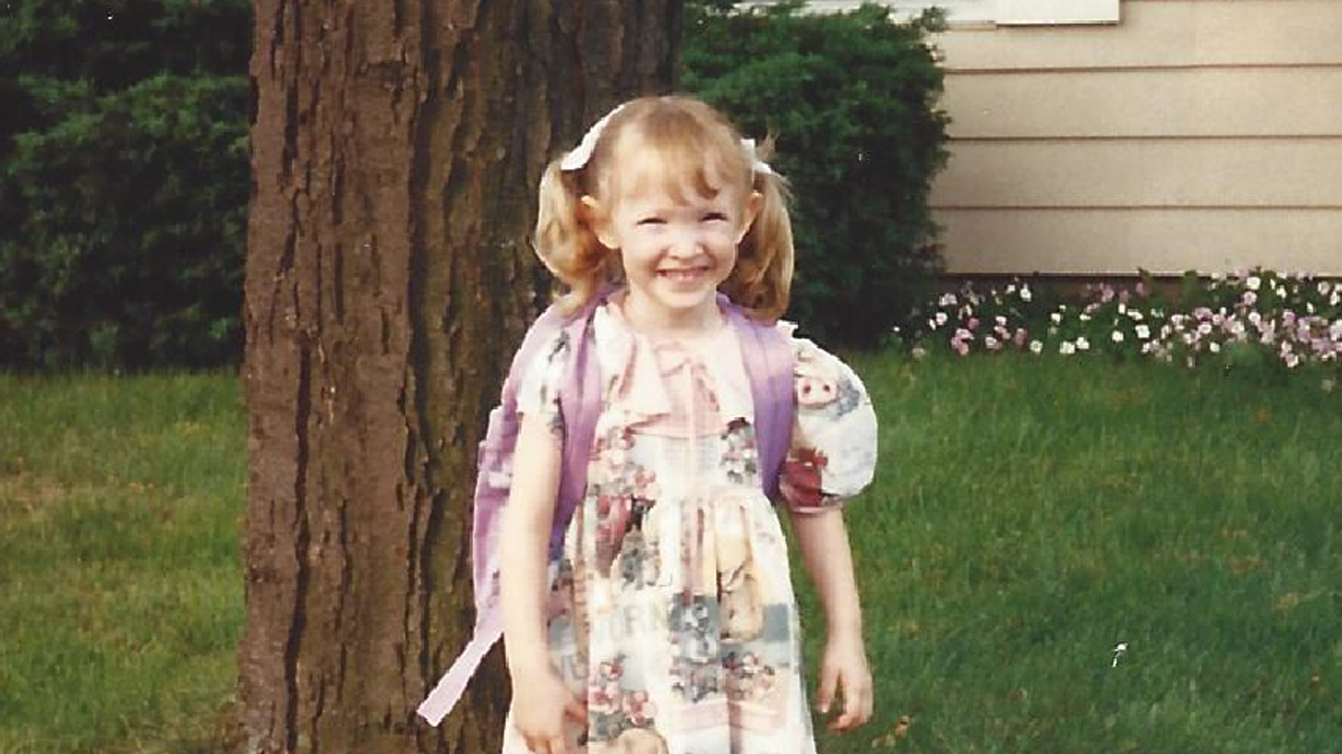 A photo of a five year old girl in a dress outside.