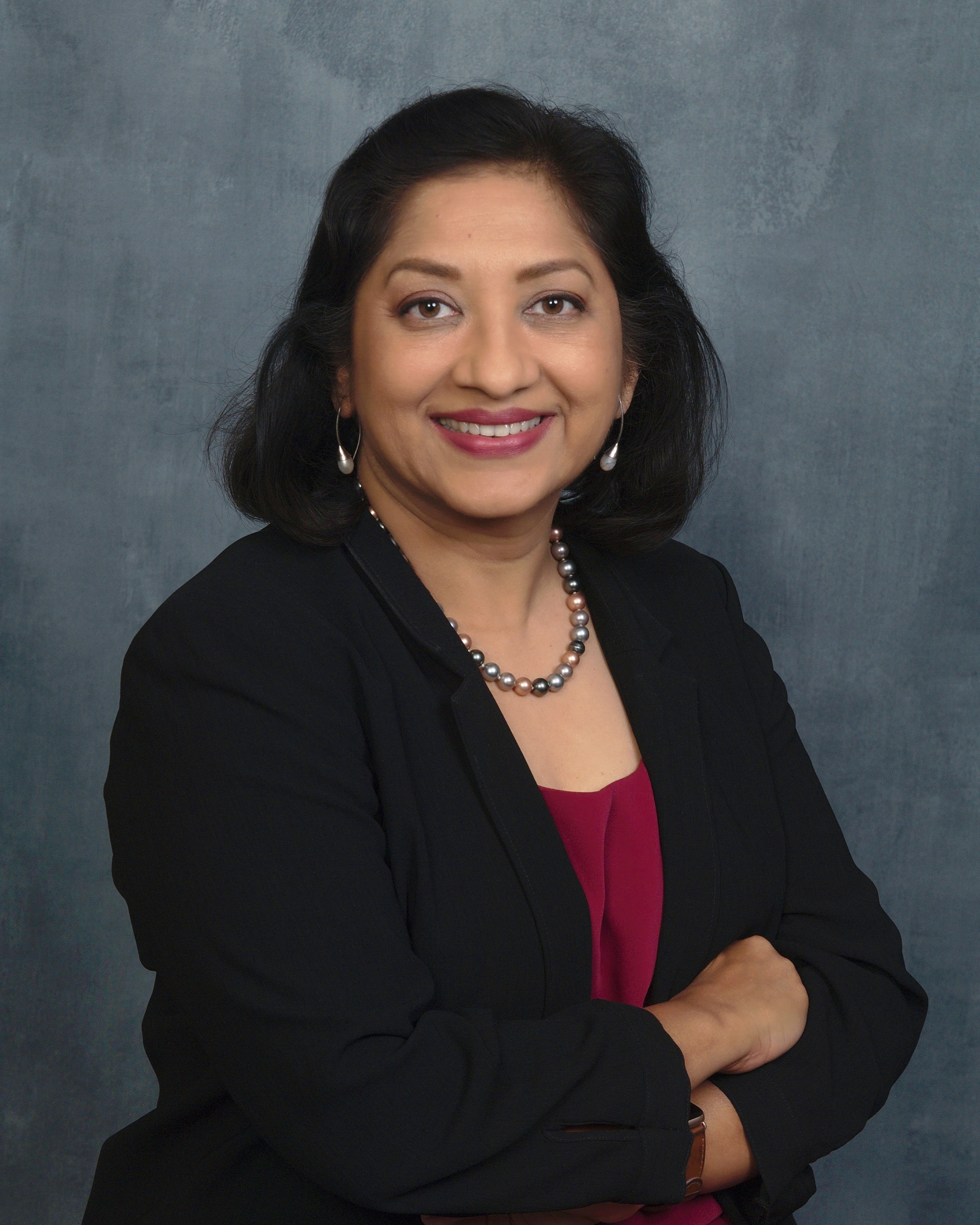 A headshot of female faculty member smiling with crossed arms.