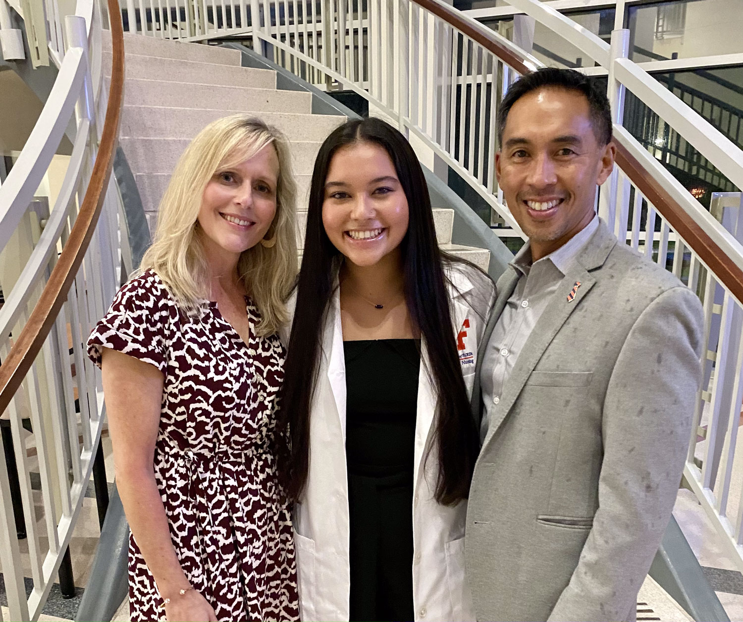A nursing graduate and her parents pose for a photo