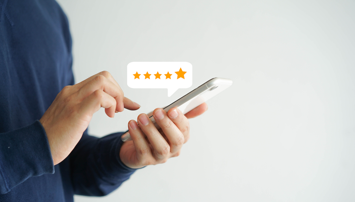 A person holding a smartphone while tapping out a five star review