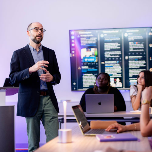 Nathan Carpenter speaks to student in social media analytics lab