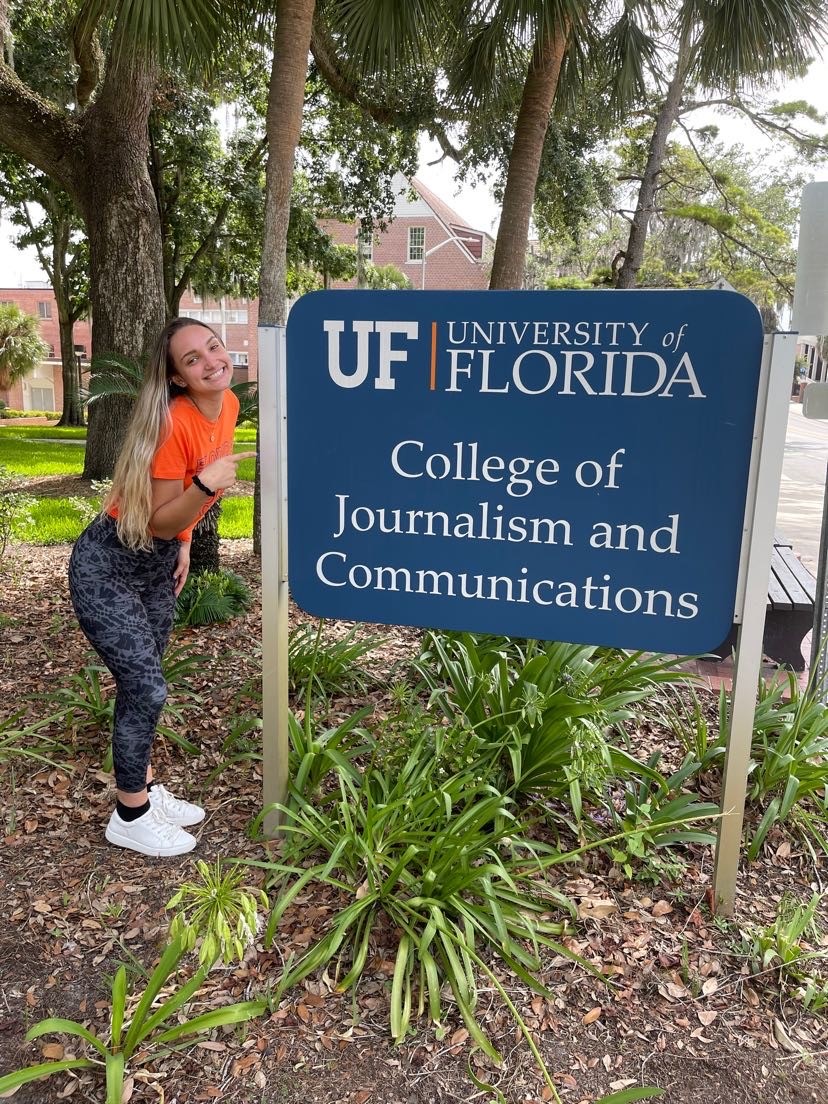 A student poses next to journalism school sign.