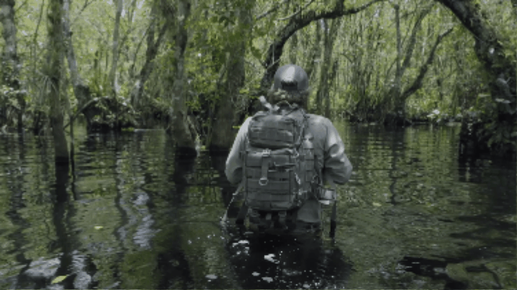 A man wading through a swamp.