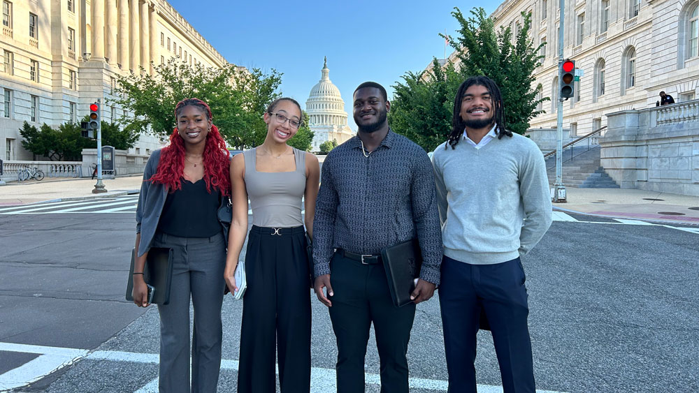 A group of student athletes pose in front of the US Capitol building.