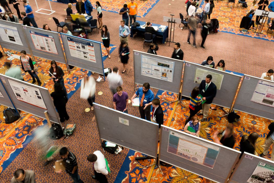 An overhead view of students standing in front of and visiting research posters