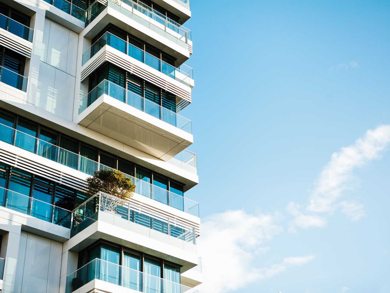 Looking up at the balconies of condos with a blue sky behind them