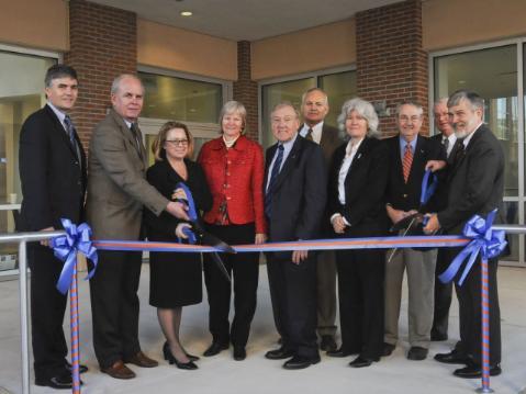 Several people stand in front of a ribbon to inaugurate a new building